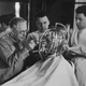 Hollywood cosmetics expert Max Factor (1877 - 1938, left) takes precise measurements of a young woman’s head and face with a ‘Beauty Calibrator’, device, circa 1932.